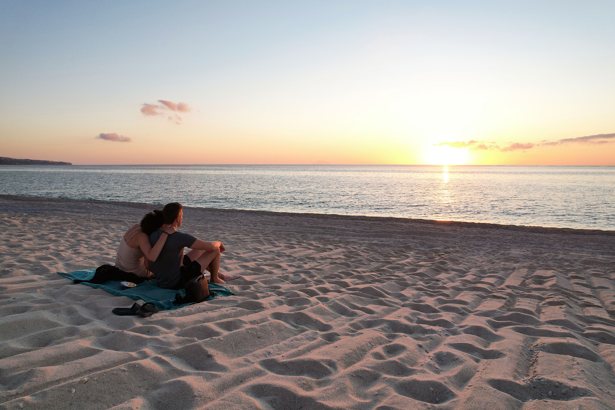Julian, the owner of the company, sitting on the beach with his girlfriend, both enjoying the sunset. This photo captures a happy and serene moment, reflecting on their sabbatical, creating a lasting memory.